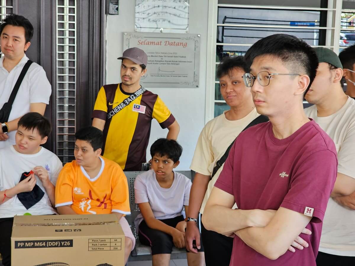 Residents and volunteers standing beside the Selamat Datang plaque inside PKKII Insan Home in Kuala Lumpur