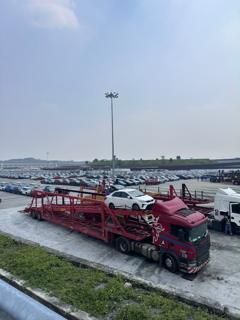 Red Scania car carrier transporter loaded with a white Perodua unit at the Sungai Choh stockyard loading hardstand