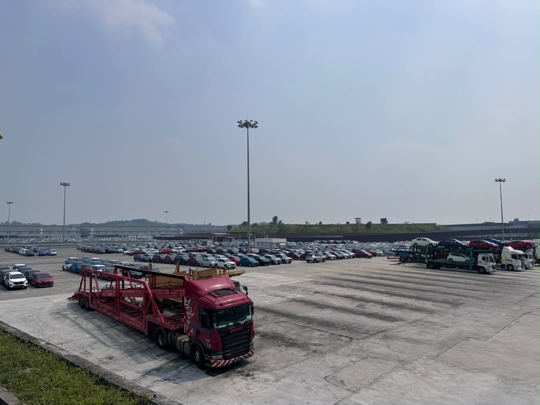Elevated view of Perodua's vehicle stockyard at Sungai Choh, Rawang, with hundreds of finished vehicles in rows and car carrier transporters staged for loading